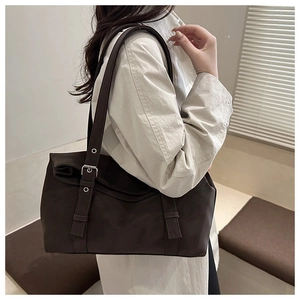 Détail du sac à bandoulière en similicuir marron foncé avec boucles argentées et fini mat