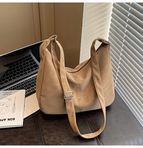 Dettaglio della borsa tote in pelle color cammello con tracolla vicino a un laptop