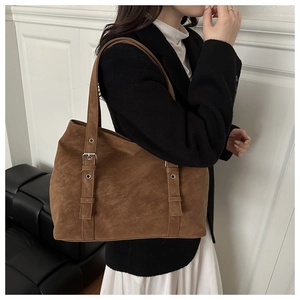 Gros plan d'un sac cabas marron en similicuir avec boucles argentées porté à l'épaule