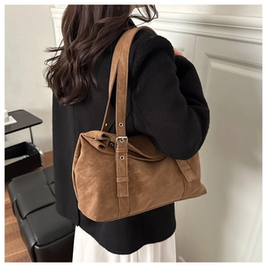 Detail of adjustable metal buckle and strap on a brown oversized tote bag