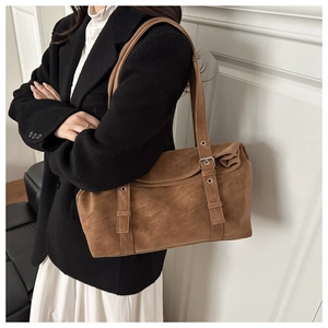 Détail d'un cabas marron en daim avec sangles à boucles argentées porté par un modèle