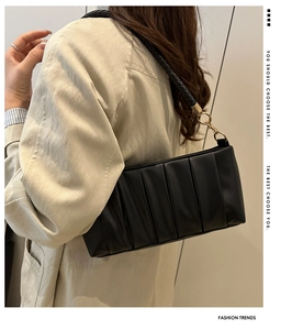 Detail of black pleated cloud bag with woven leather strap and golden metal rings