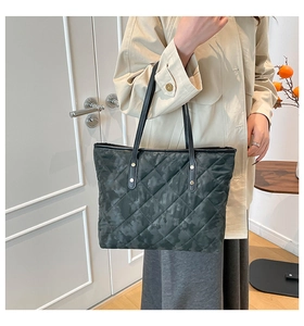 Detail of quilted camouflage tote bag with black leather straps and gold rivets