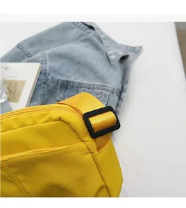 Close-up of bright yellow nylon crossbody bag featuring adjustable wide shoulder strap