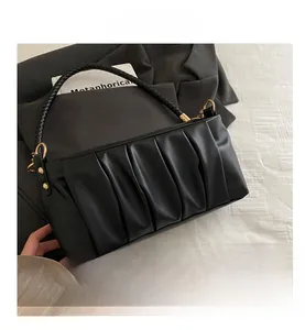 Detail of ruched black shoulder bag with woven leather handle and gold hardware accents