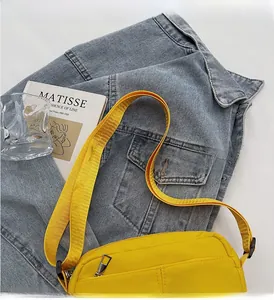 Close-up of vibrant yellow nylon crossbody bag with wide strap and silver zippers