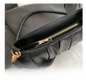 Close-up of smooth gold zipper and black pleated texture on the chic cloud bag