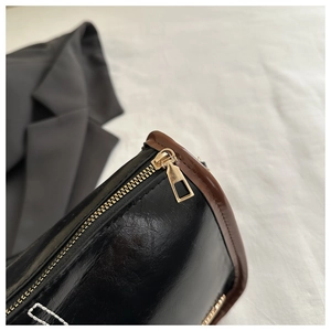 Gros plan sur la fermeture éclair dorée et la texture du cuir noir du sac à bandoulière