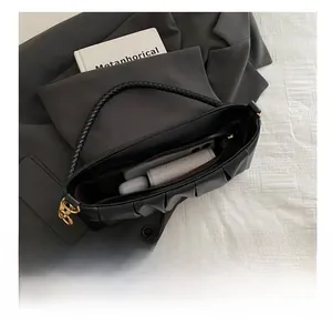 Top view of black pleated underarm bag showing spacious interior with phone and wallet