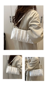 Detail view of white ruched shoulder bag featuring woven strap and golden hardware