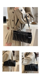 Detail of ruched black cloud bag with woven shoulder strap and gold hardware accents
