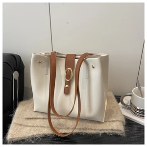 Detail of soft white faux leather tote with brown shoulder straps and gold buckle accent