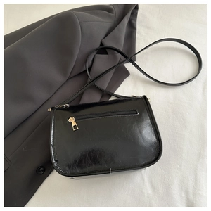 Détail de la poche zippée arrière sur un sac à bandoulière en cuir noir brillant chic