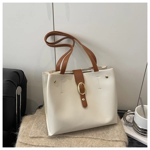 Detail of soft white leather tote bag with brown handles and golden metal buckle
