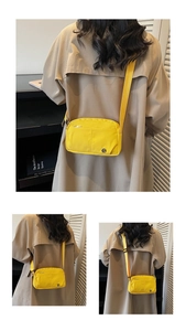 Detail view of yellow canvas crossbody bag featuring multi-zip pockets and adjustable strap