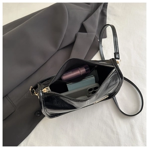 Vue intérieure montrant le rangement spacieux d'un sac bandoulière en cuir noir brillant