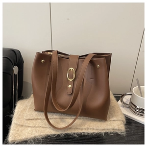 Detail of soft brown leather tote bag showing gold metal hardware and textured finish