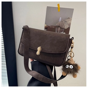 Detail showing deep brown matte leather bag with peanut gold clasp and plush charm