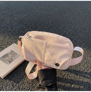 Detail of light pink nylon crossbody bag with zipper pocket and adjustable strap