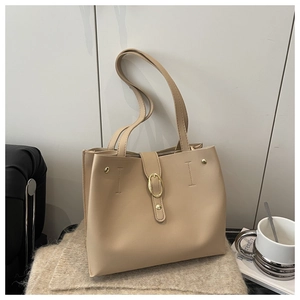 Detail of soft beige leather tote bag featuring a golden oval metal buckle and dual handles