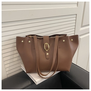 Detail of brown leather tote bag with gold buckle and rivets on top zipper closure