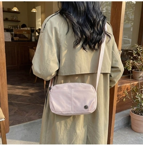 Nylon crossbody bag shown on model featuring zip closure and front pocket detail