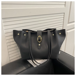 Detail of black faux leather tote bag featuring gold buckle and metallic zipper closure
