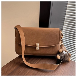 Detail of a brown matte baguette bag featuring a gold peanut-shaped twist lock and plush charm