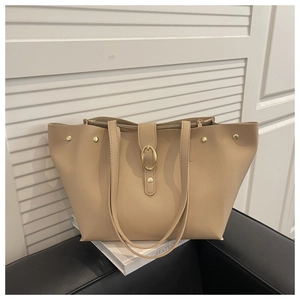 Macro shot of oat beige soft leather tote bag with gold oval buckle and metal studs