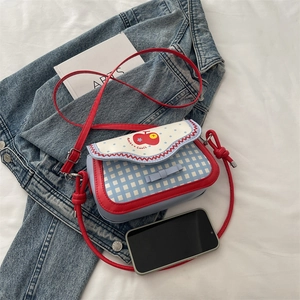 Checkered red apple crossbody bag with blue polka dots and a red leather strap