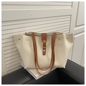 Detail of cream leather bucket bag with brown handles and gold hardware accents