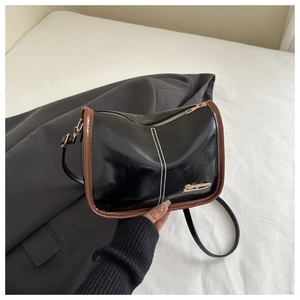 Détail du sac bandoulière vintage en cuir ciré avec bordure contrastée et plaque dorée