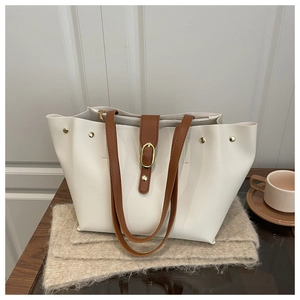 Detail of cream soft leather bucket bag with brown straps on a rustic wood surface