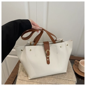 Detailed shot of white tote bag with brown straps and golden magnetic buckle
