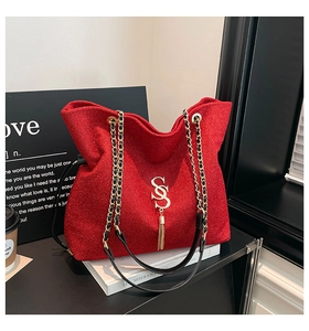 Close-up of a sparkly red tote bag featuring a gold letter S emblem and tassel detail