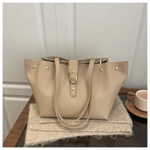 Detail of apricot large faux leather tote bag with gold hardware on a wooden table