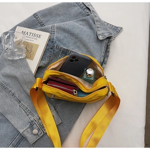 Macro view of yellow nylon crossbody bag interior showing phone and wallet storage