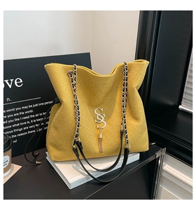 Detail of yellow glitter tote bag featuring gold SS logo, tassel, and chain strap