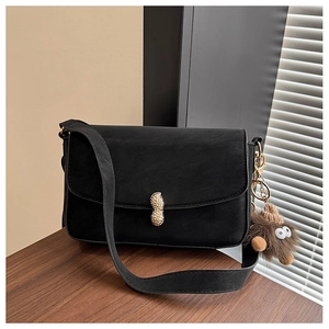 Detail of black matte shoulder bag featuring a unique gold peanut-shaped metal buckle