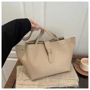 Detail of beige faux leather tote bag with gold oval buckle and interior zipper compartment