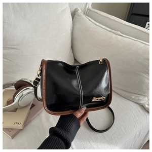 Détail du sac à bandoulière noir brillant vintage avec liseré marron et logo doré