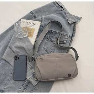 Detail of grey waterproof nylon crossbody bag with logo on casual denim jacket