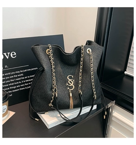 Detail of glitter fabric tote bag featuring gold S-letter logo and chain strap