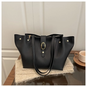 Detail of black soft leather bucket bag with gold hardware and side rivet accents