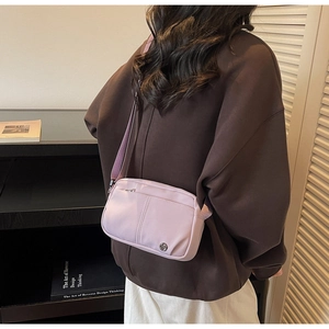 Detail of light purple nylon crossbody bag featuring adjustable strap and metal logo