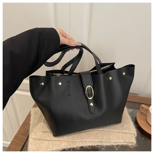 Detail of black tote bag featuring gold rivet studs and textured synthetic leather