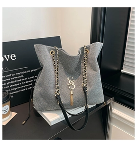 Macro detail of grey sequin tote bag with gold SS logo and elegant tassel charm