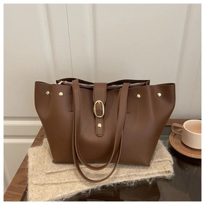 Close-up of brown soft leather tote bag with gold buckle detail and zipper on cozy setting