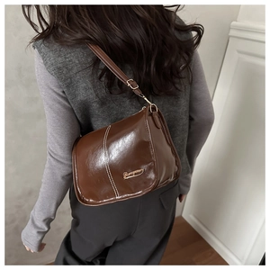 Détail du sac à bandoulière marron en cuir PU avec surpiqûres blanches et logo doré