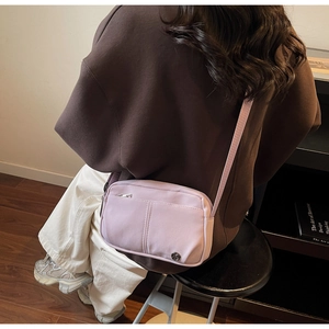 Detail of light purple nylon crossbody bag with water-resistant fabric and metal logo